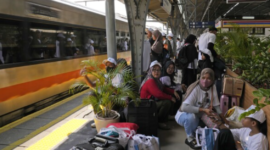 Penumpang menunggu kedatangan kereta api di peron stasiun selama libur Isra’ Mi’raj.
(Foto: AP Photo)