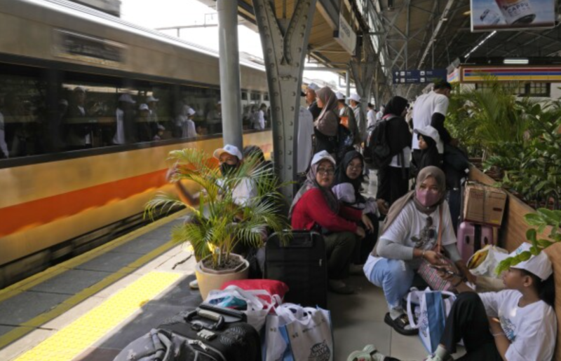 Penumpang menunggu kedatangan kereta api di peron stasiun selama libur Isra’ Mi’raj.
(Foto: AP Photo)