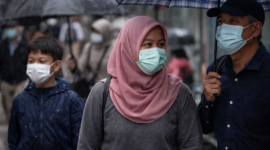 Warga menggunakan masker saat musim hujan sebagai langkah pencegahan infeksi saluran pernapasan akut.