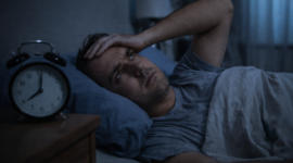 Seseorang terjaga di tempat tidur pada malam hari akibat gangguan tidur atau insomnia.