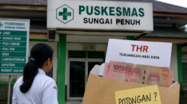 Seorang tenaga kesehatan berdiri di depan Puskesmas Sungai Penuh dengan ilustrasi amplop THR, menggambarkan dugaan potongan tunjangan dan tekanan terhadap pegawai.