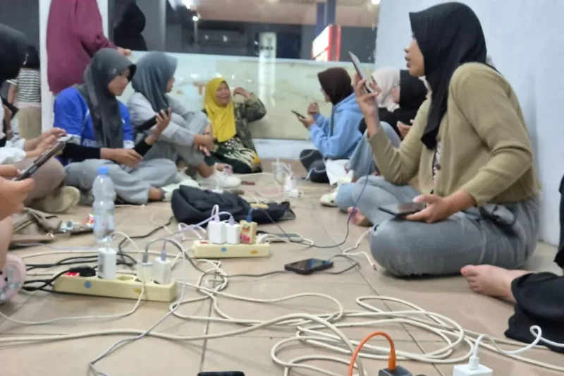 Sejumlah warga mengisi daya gawai di lokasi yang tidak terdampak pemadaman listrik di Kota Padang Jumat (22/5) malam.(Poto : ANTARA ).