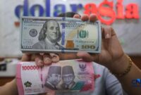 Foto: Petugas menjunjukkan uang pecahan dolar Amerika Serikat (AS) dan rupiah di Dolar Asia Money Changer, Jakarta, Rabu (8/7/2026). (CNBC Indonesia/Faisal Rahman)