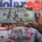 Foto: Petugas menjunjukkan uang pecahan dolar Amerika Serikat (AS) dan rupiah di Dolar Asia Money Changer, Jakarta, Rabu (8/7/2026). (CNBC Indonesia/Faisal Rahman)