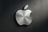 Logo Apple berbahan logam perak dengan tekstur melingkar yang elegan, terpasang pada dinding beton gelap.(poto: AI).