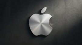 Logo Apple berbahan logam perak dengan tekstur melingkar yang elegan, terpasang pada dinding beton gelap.(poto: AI).