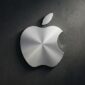 Logo Apple berbahan logam perak dengan tekstur melingkar yang elegan, terpasang pada dinding beton gelap.(poto: AI).