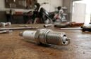 Ilustrasi busi motor di meja bengkel, komponen vital penentu tenaga mesin dan efisiensi bahan bakar kendaraan bermotor.(poto: oegopost.id).