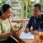Petugas Mantri BRI menjelaskan tabel simulasi angsuran KUR kepada pelaku usaha mikro di warung kelontong.(ilustrasi poto: AI).